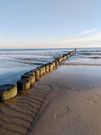 Wooden posts in sea against sky