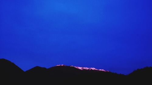 Silhouette mountains against clear blue sky at night