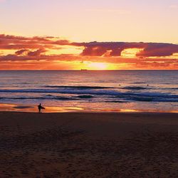 Silhouette man standing on beach against sky during sunset