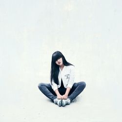 Young woman sitting on white background