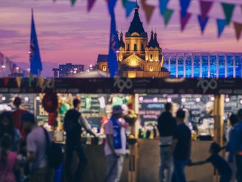 People on illuminated building in city at dusk