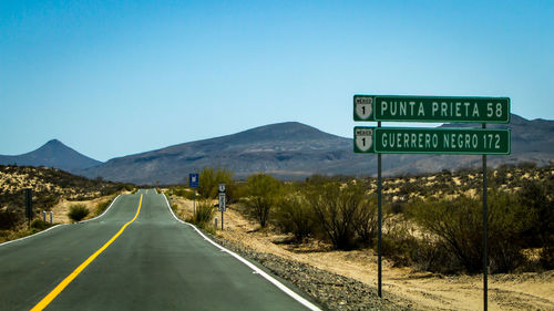 Road sign against clear blue sky