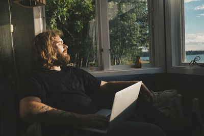 Man looking at camera while sitting on sofa at home