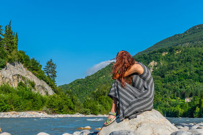 Rear view of woman against mountains and blue sky