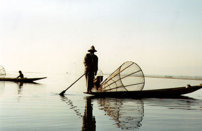 People working on boat sailing in sea against clear sky