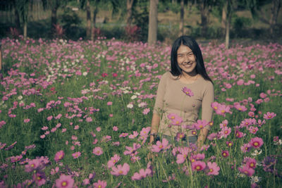 Portrait of smiling woman standing amidst flowers