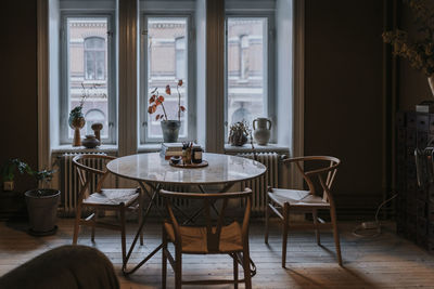 Chairs and tables arranged by window in living room at home