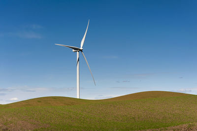 Windmill on hills against blue sky