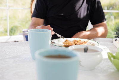 Midsection of man holding fork by food in plate