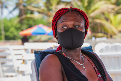 African woman sitting on a beach with black mouth mask in labadi accra ghana west africa
