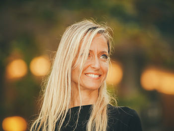 Close-up of smiling woman with blond hair looking away outdoors