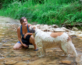 Full length of a smiling young woman sitting dog