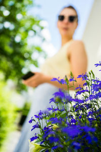 Low angle view of woman standing on purple flowering plants