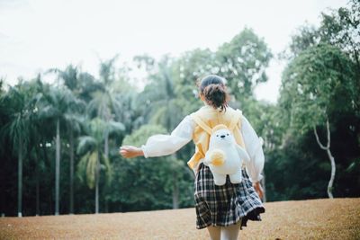 Rear view of girl against trees