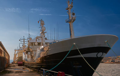 Ship moored at harbor against sky