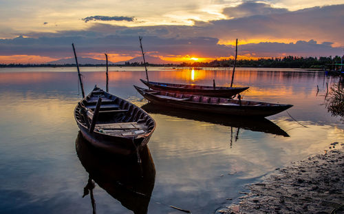 Boats moored in sea at sunset