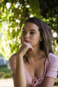 Teenage girl looking away against trees at park