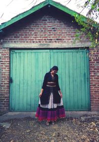 Full length of woman standing against door of building