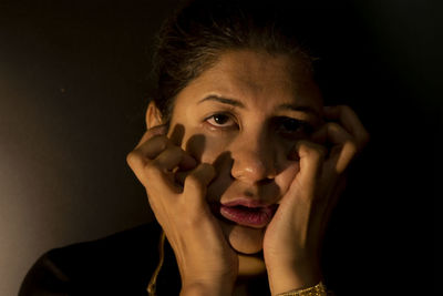 Close-up portrait of a serious young woman over black background