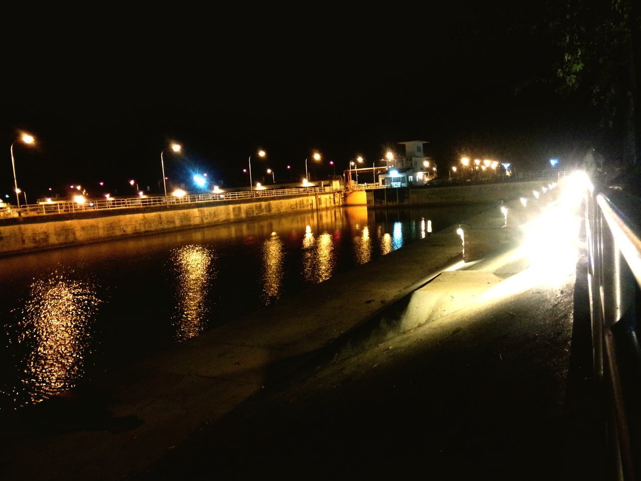 night, illuminated, water, architecture, built structure, street light, building exterior, reflection, river, lighting equipment, city, bridge - man made structure, clear sky, the way forward, railing, connection, dark, outdoors, canal, light - natural phenomenon