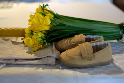 Close-up of yellow flowers and baby shoes on baptism day