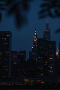 Illuminated buildings in city against sky at dusk