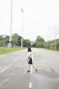 Rear view of woman running on road against sky
