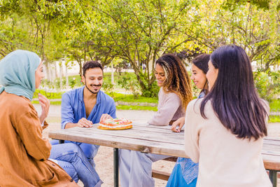 Portrait of smiling friends sitting on field