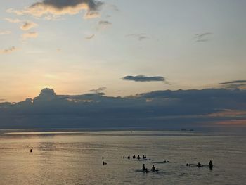 Silhouette people on beach against sky during sunset
