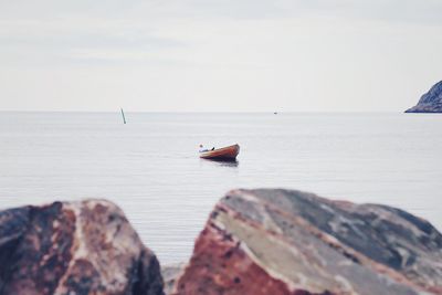 Boat on rock in sea against sky