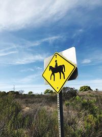 Road sign on field against sky