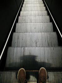 Low section of man standing on escalator