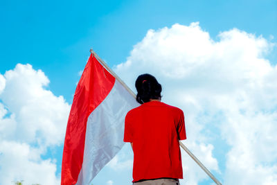 Rear view of man with umbrella against sky