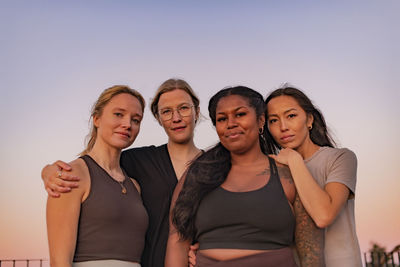 Portrait of smiling friends standing against sky