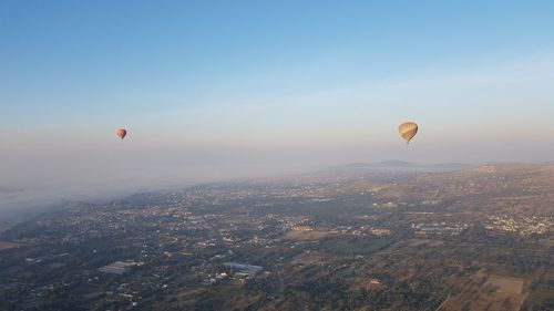 Hot air balloons flying in city against sky