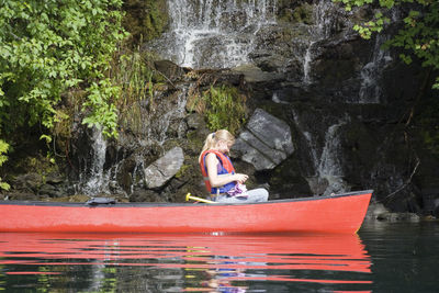 Woman sitting on rock by river