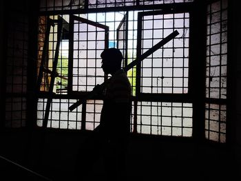 Silhouette woman standing against window