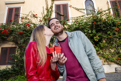 Beautiful happy couple with valentines day gift. the woman kisses her boyfriend.