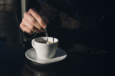 Midsection of woman holding coffee on table