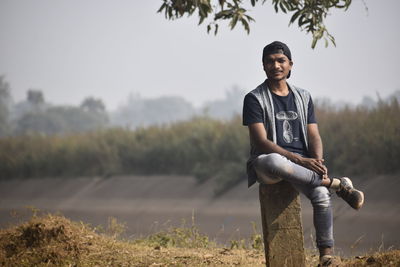 Portrait of young man sitting on stone