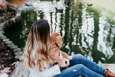 Dog with woman by pond at park