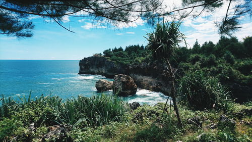 Scenic view of rocks by sea against sky