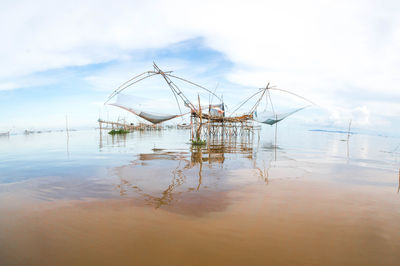 Cranes in sea against sky