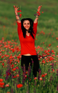 Portrait of smiling young woman standing against plants