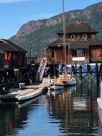 Boats moored on river by houses against sky