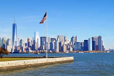 American flag by river with city in background