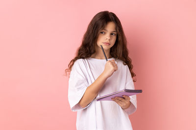 Young woman standing against pink background