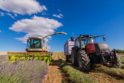 Tractor on field against cloudy sky