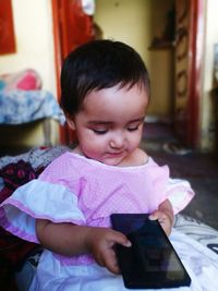 Cute baby girl holding mobile phone at home