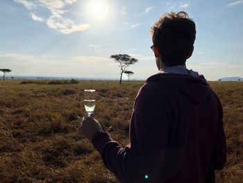 Rear view of young man holding champagne flute while standing on land